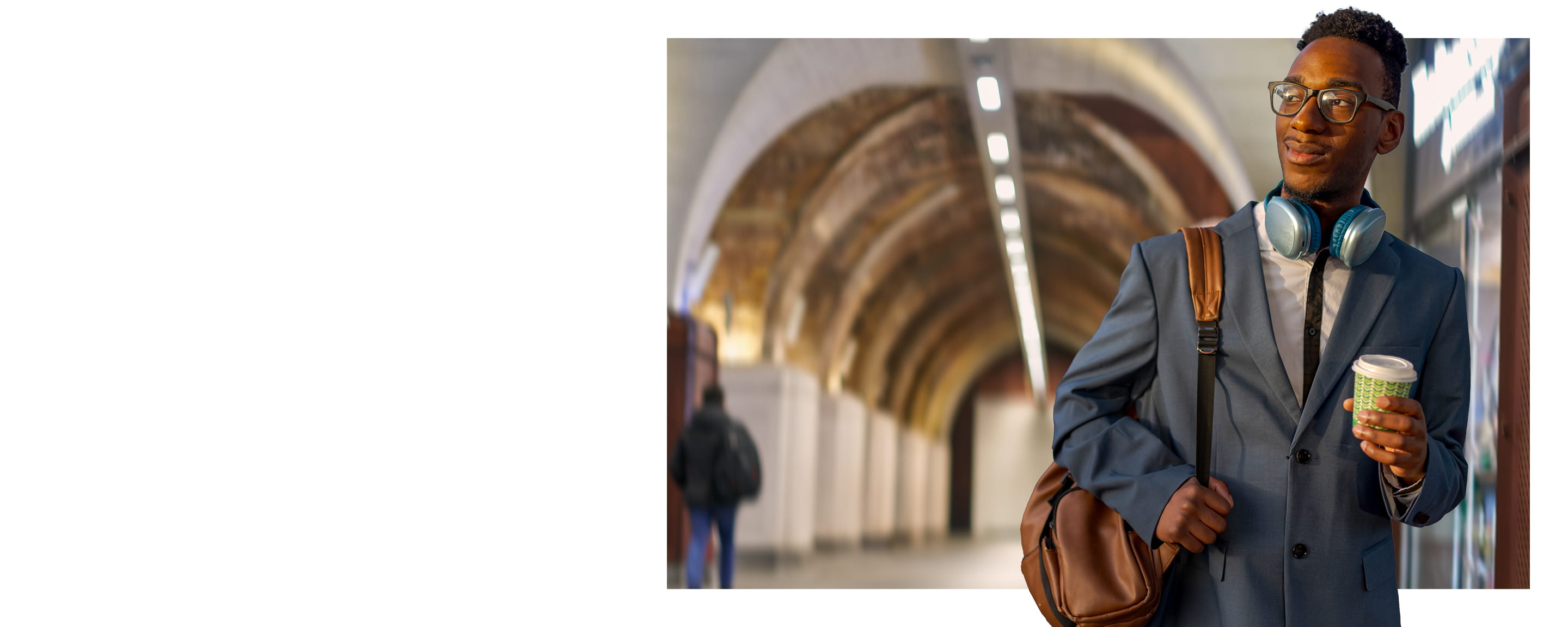 Man holding a coffee walking through a train station