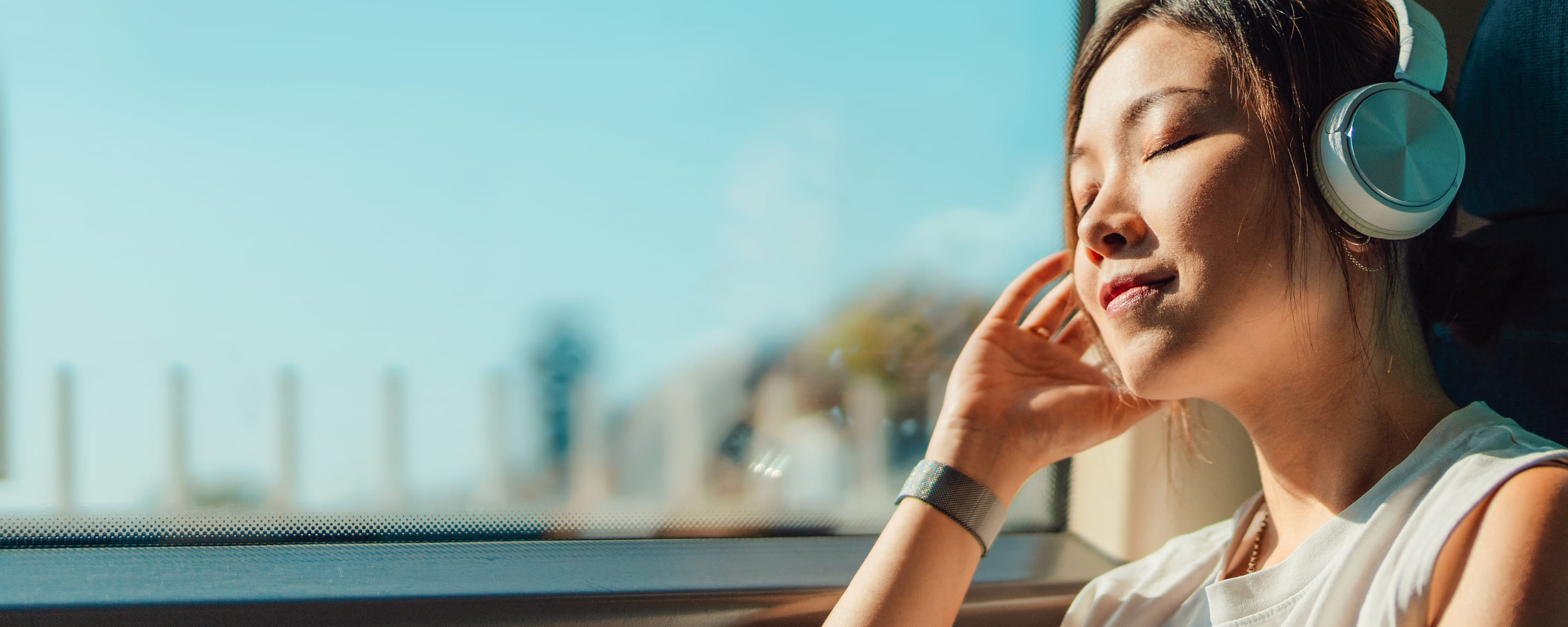 woman wearing headphones looking out train window